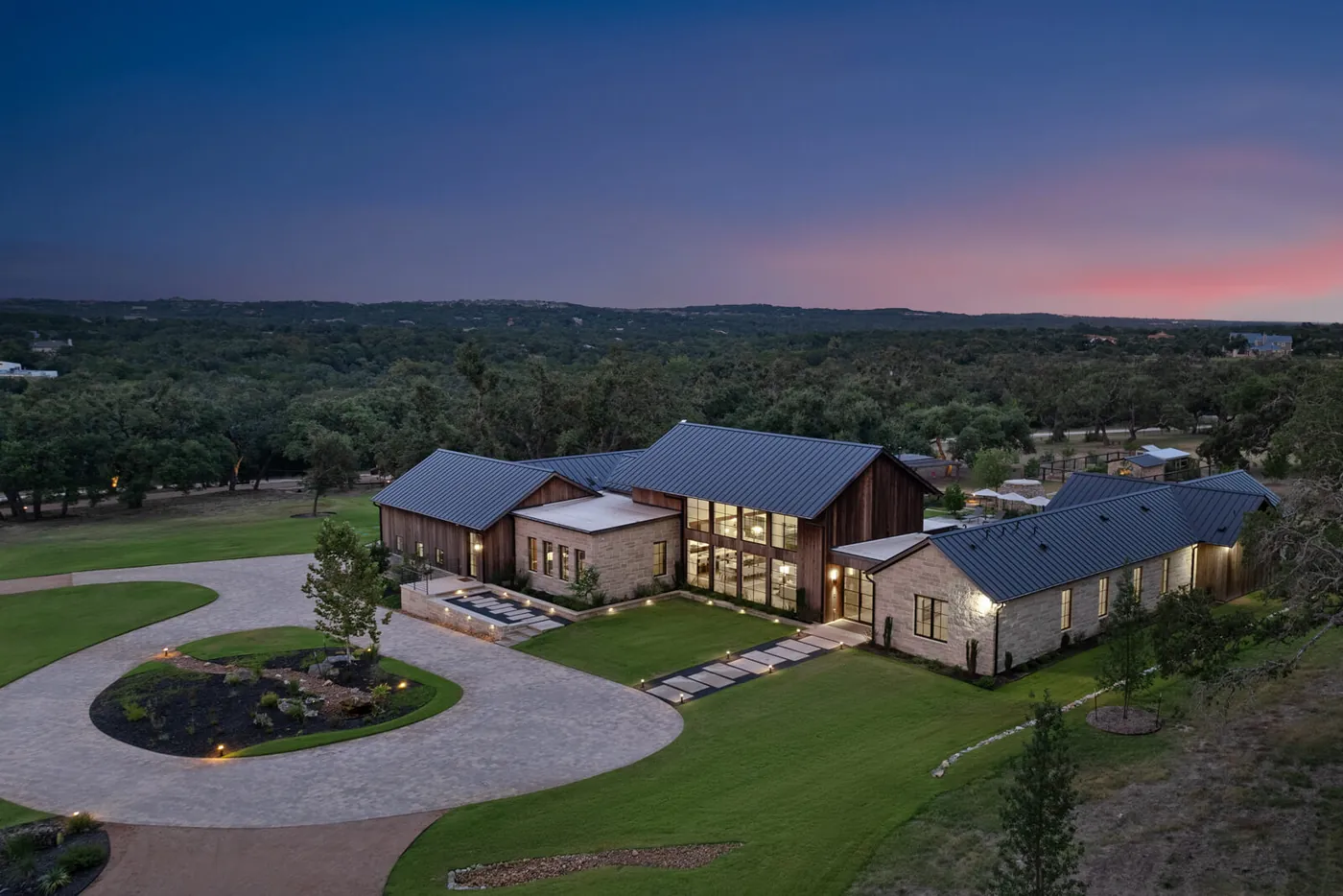 Hill Country estate with circular paver driveway at dusk